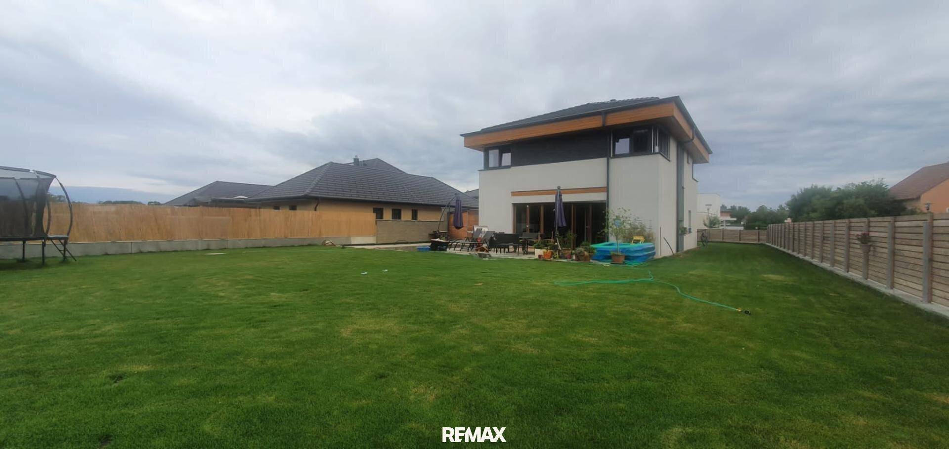 Weitläufiger Garten mit Rasenfläche, Trampolin und Blick auf die Hausrückseite.