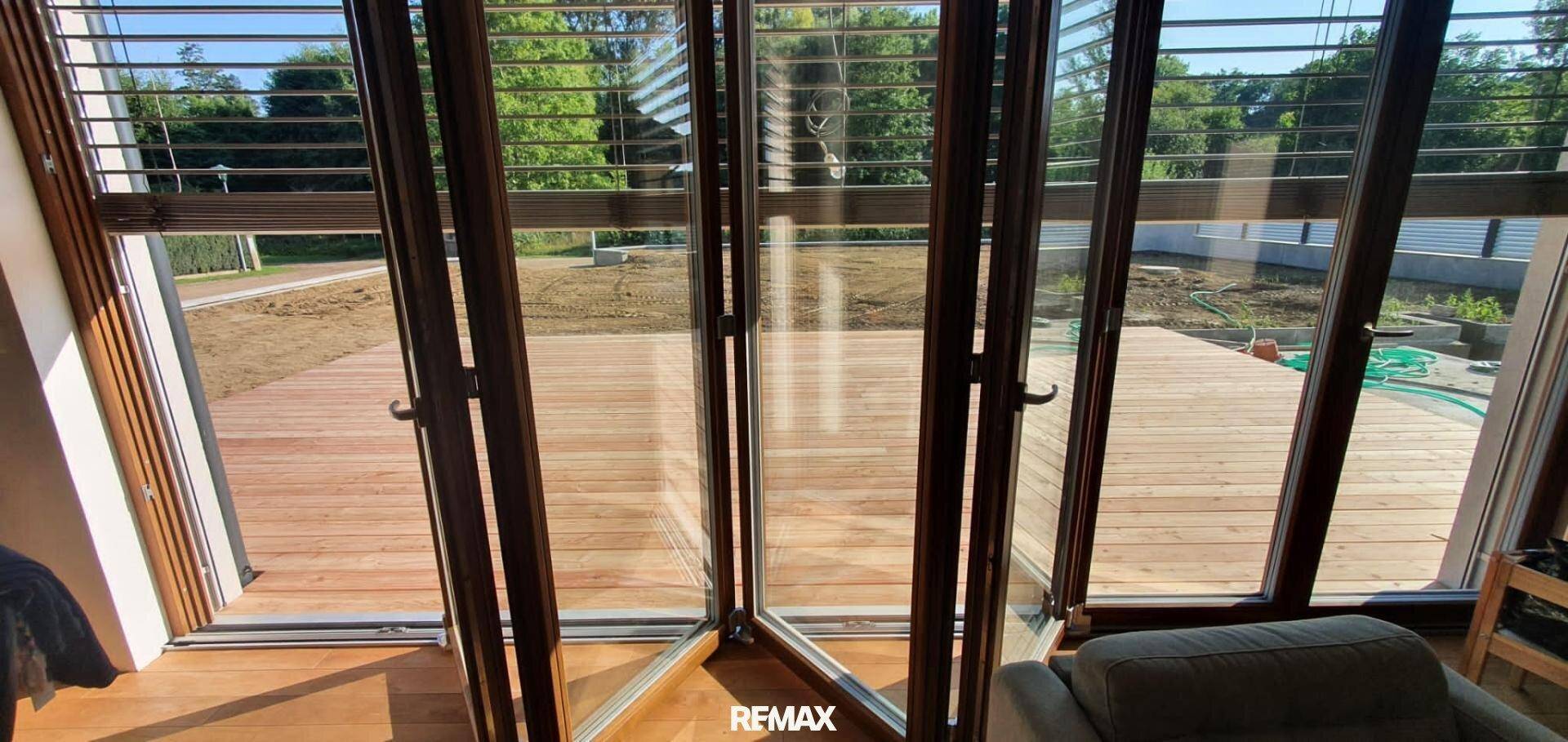 Große Falttüren öffnen den Wohnbereich zur Holzterrasse und zum Garten.