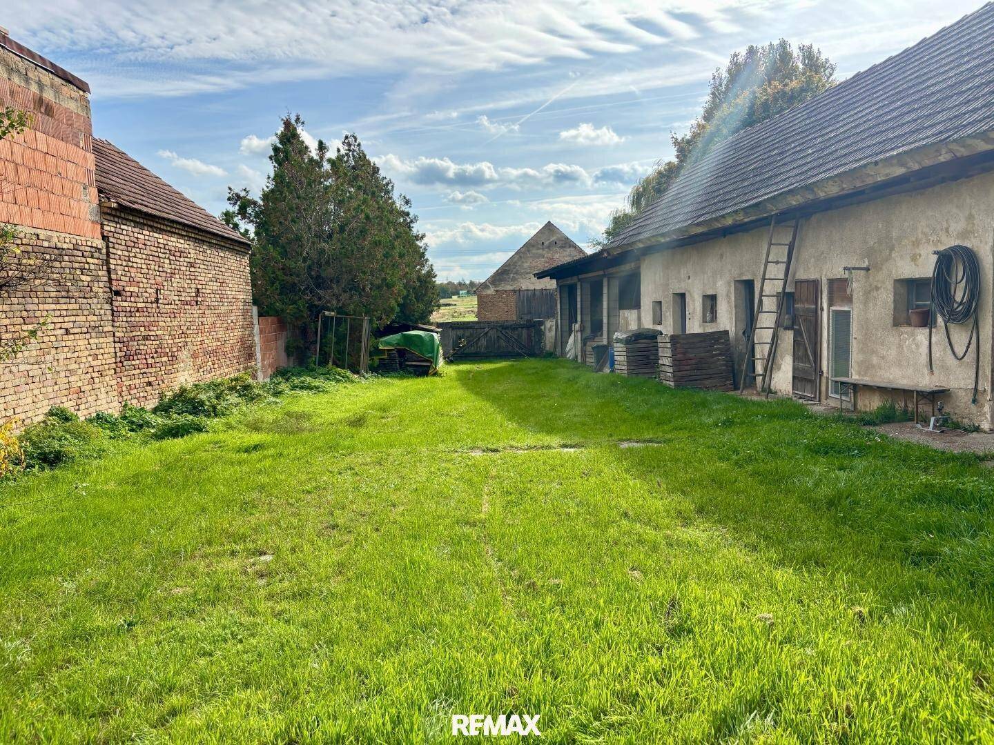 Weitläufiger Gartenbereich eines ländlichen Anwesens mit Nebengebäuden und viel Grünfläche.