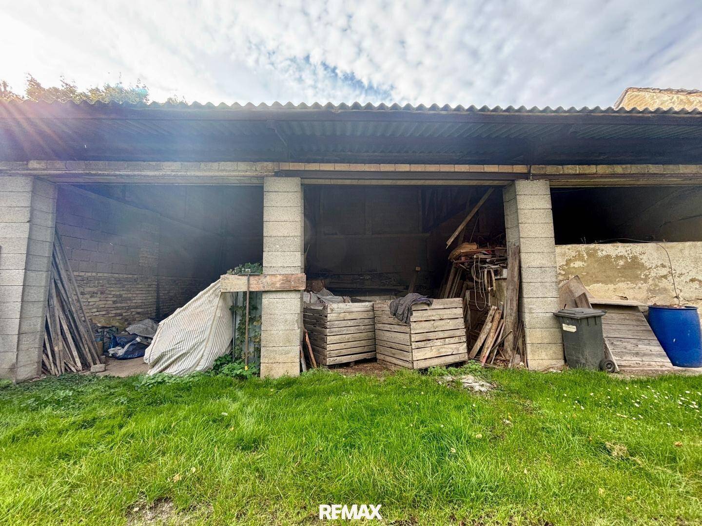 Offene Garage oder Schuppen mit Lagerflächen und Wellblechdach auf dem Grundstück.