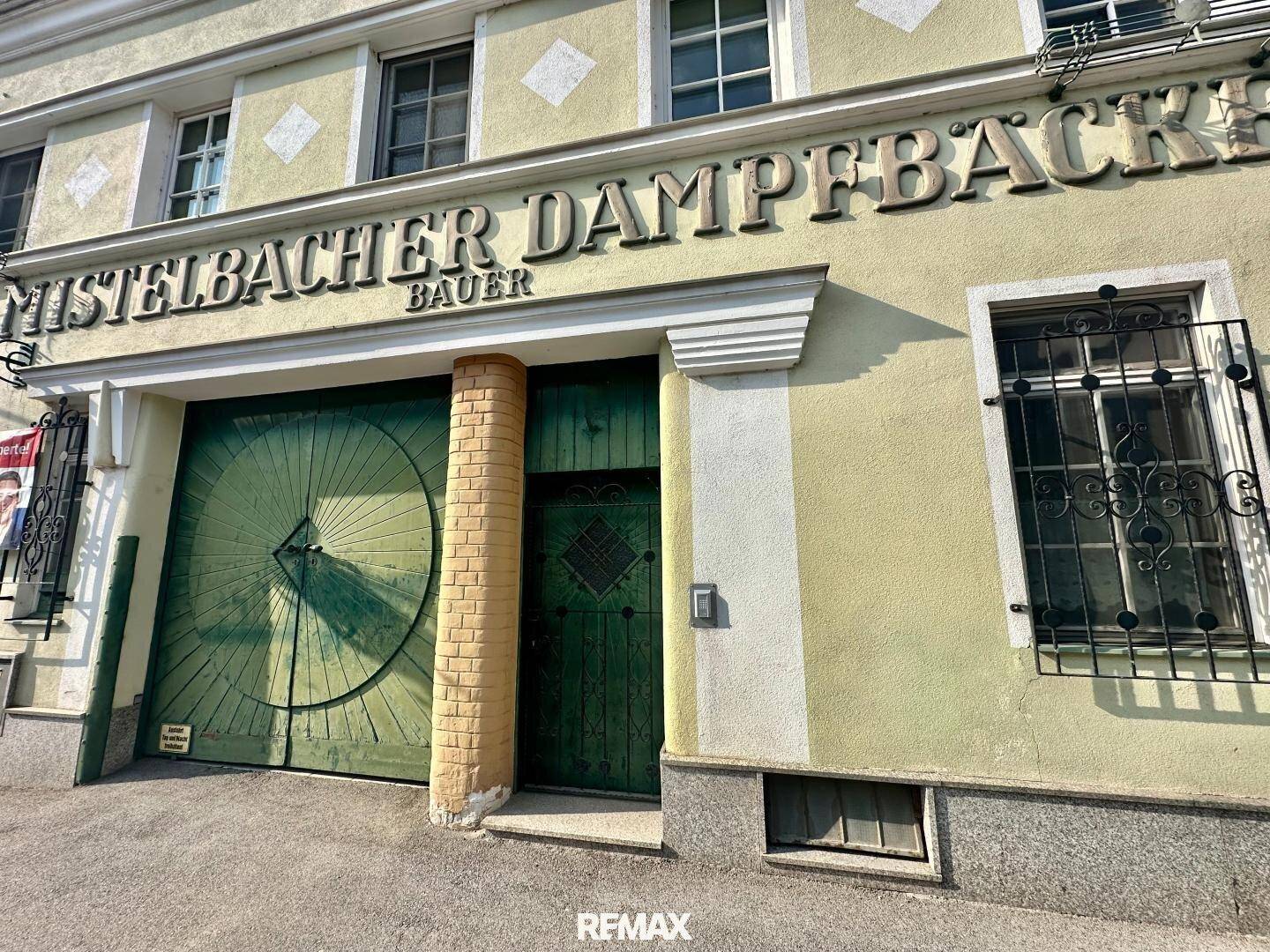 Historische Fassade mit großen Holztoren und traditioneller Beschriftung, die den Charme des Gebäudes unterstreicht.