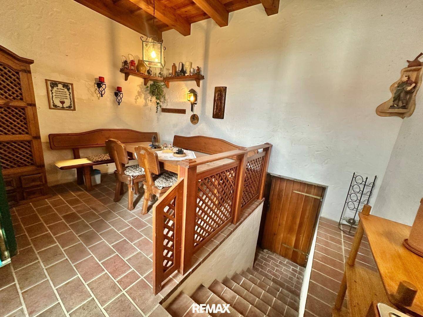 Gemütlicher Essbereich mit Holztisch und Bänken, angrenzend an eine Treppe mit Holzgeländer.