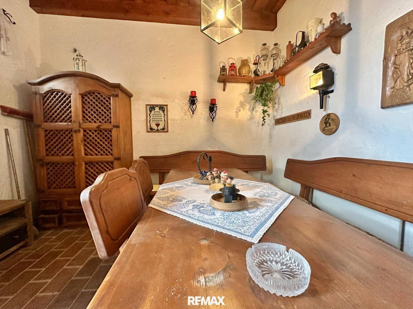 Gemütlicher Essbereich mit Holztisch, Bänken und einem traditionellen Holzschrank.