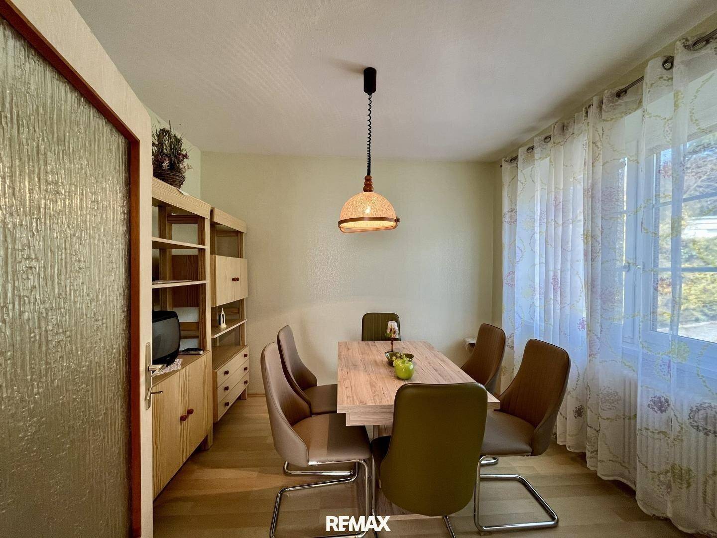 Heller Essbereich mit Holztisch, modernen Stühlen und großen Fenstern.