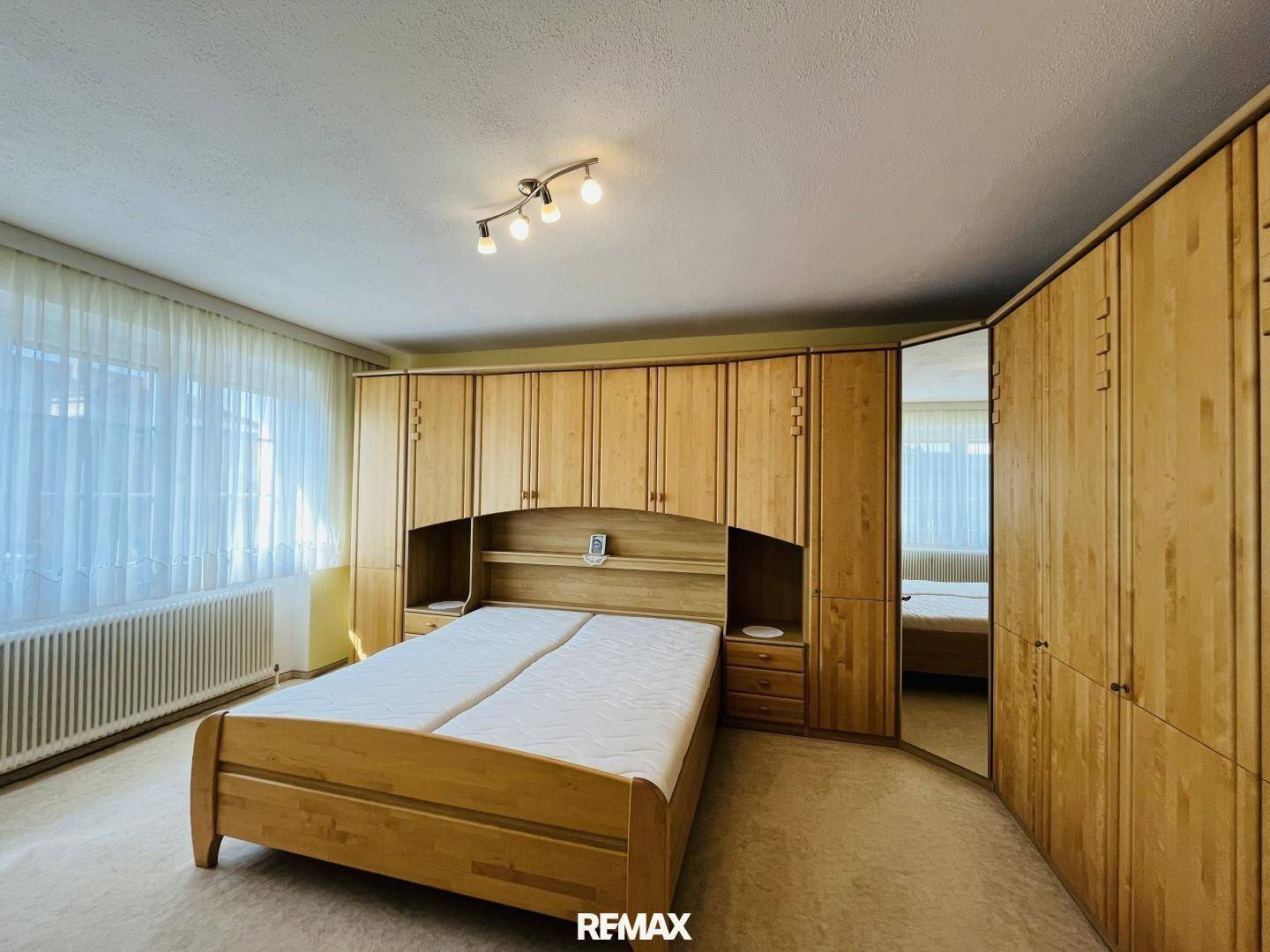Schlafzimmer mit großem Einbauschrank aus Holz und Teppichboden.