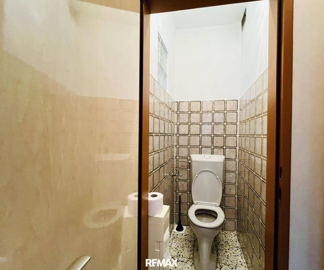 Separate Gästetoilette mit Fliesen im Retro-Stil und einfacher Ausstattung.