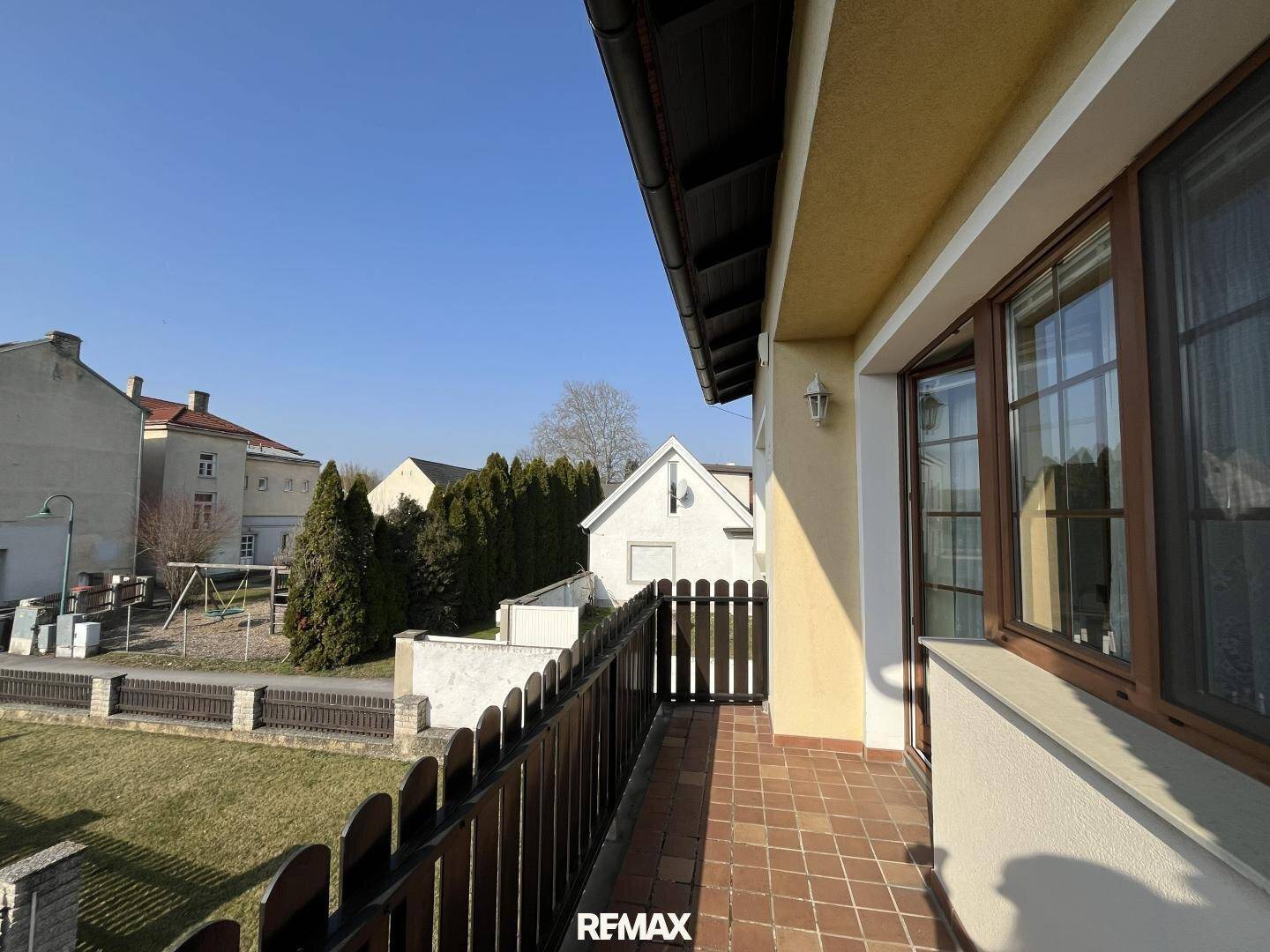 Kleiner Balkon mit Fliesenboden und Holzgeländer, ideal für sonnige Stunden.