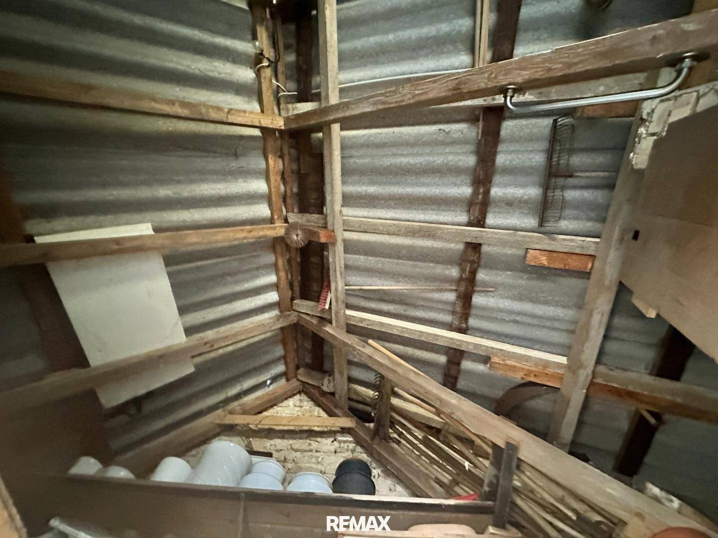 Unausgebauter Dachboden mit sichtbaren Holzbalken und Wellblechdach, bietet Stauraum.