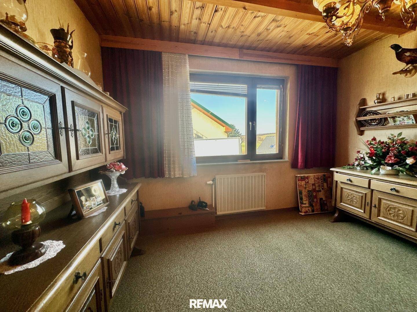 Zimmer mit rustikaler Holzdecke, Teppichboden und traditionellen Holzschränken.