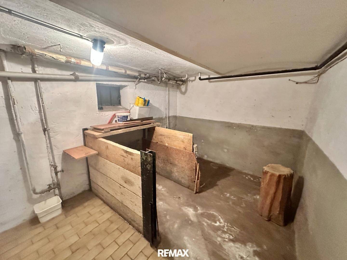 Unfertiger Kellerraum mit Betonboden, rauen Wänden und Holzkonstruktionen für Lagerzwecke.