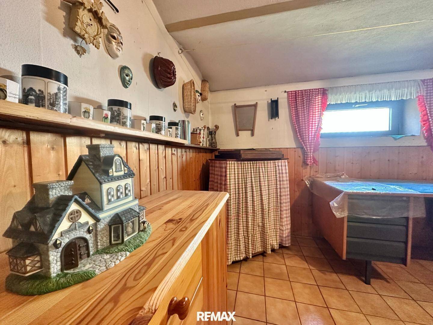 Rustikaler Raum mit Holzvertäfelung, Fliesenboden und dekorativen Elementen, inklusive kleinem Fenster.