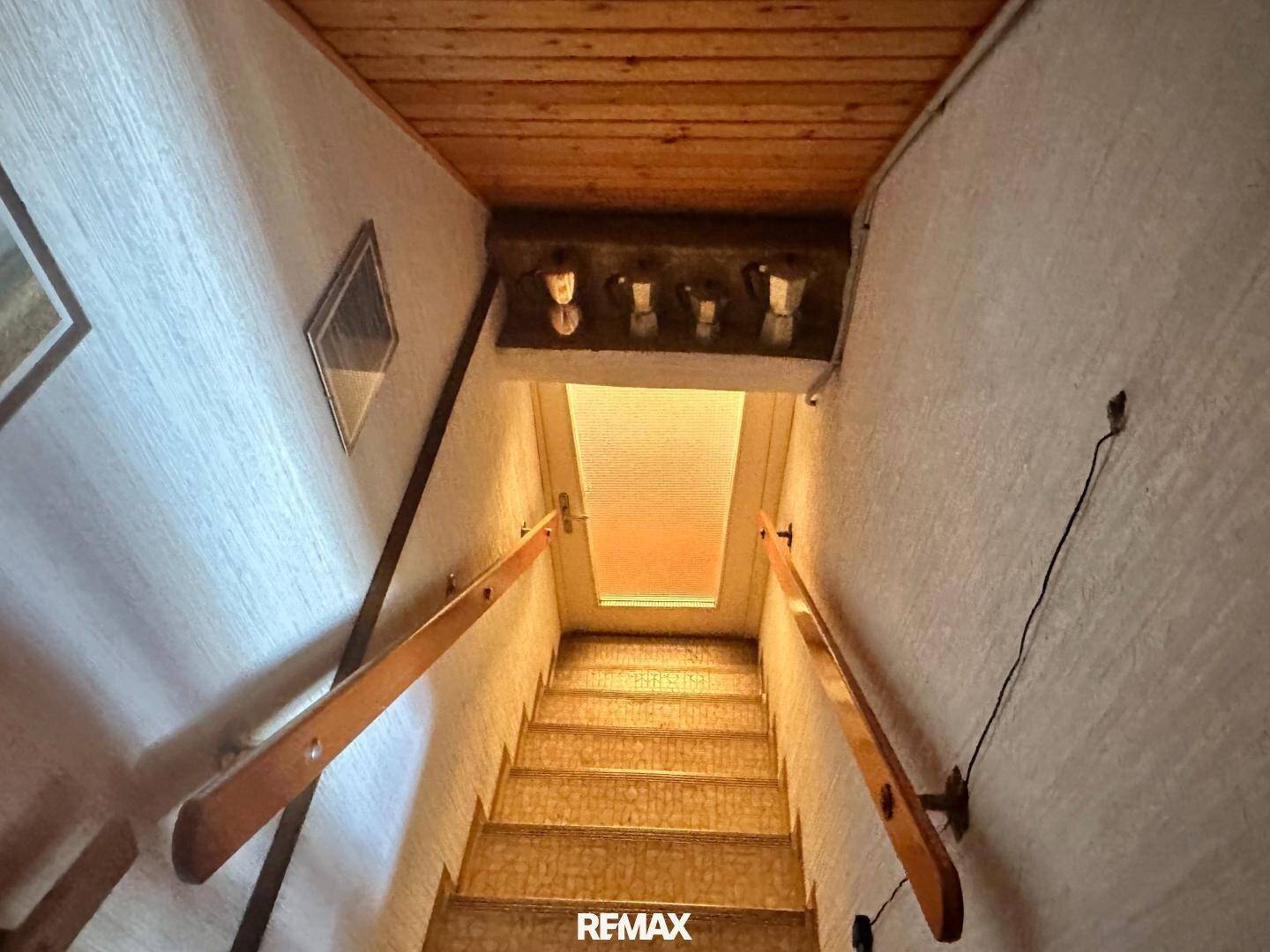 Treppenabgang mit Holzgeländer und Teppichstufen, führt in das untere Stockwerk.