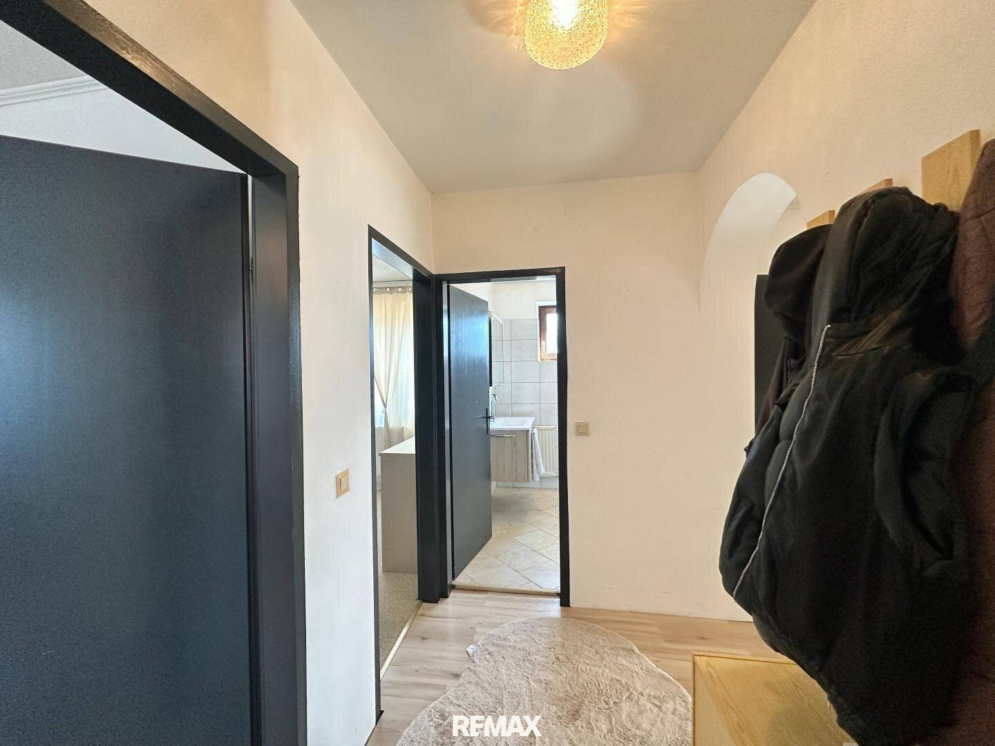 Flur mit mehreren Türen, eine davon führt zu einem Badezimmer mit Fliesenboden.