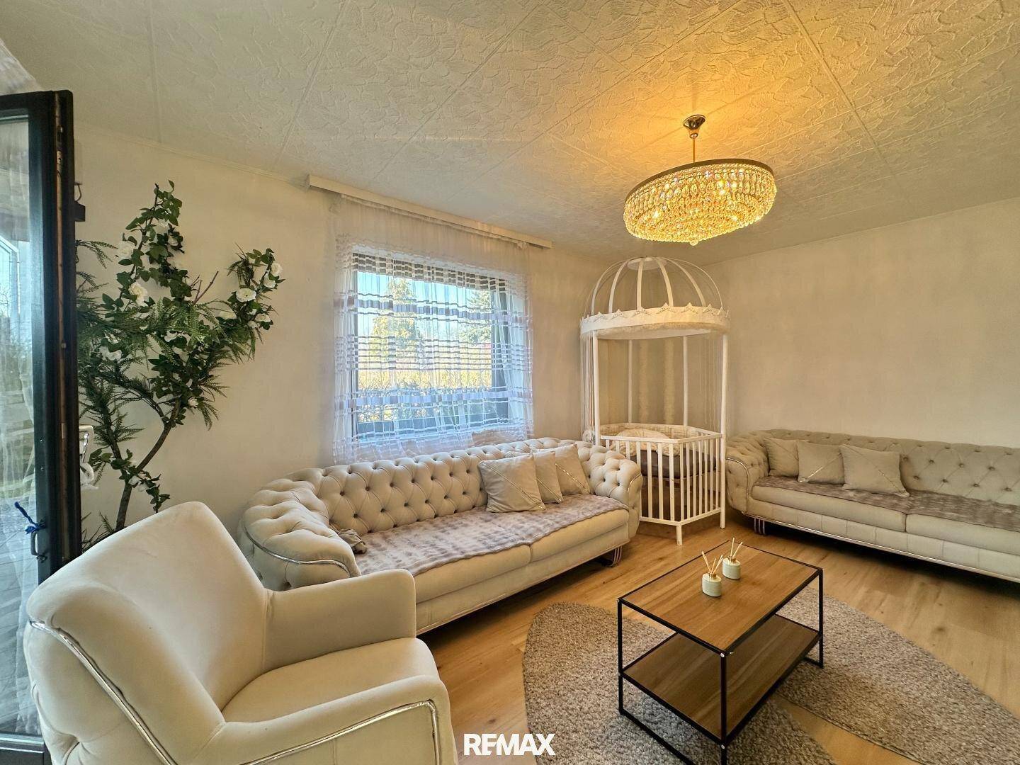 Gemütliches Wohnzimmer mit zwei Sofas, einem Couchtisch und einem eleganten Kronleuchter.
