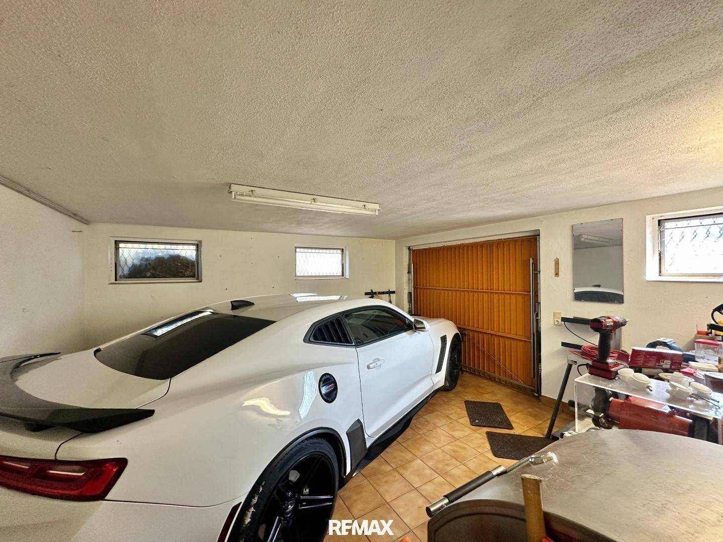 Geräumige Garage mit einem Sportwagen, Fliesenboden und Werkbank.