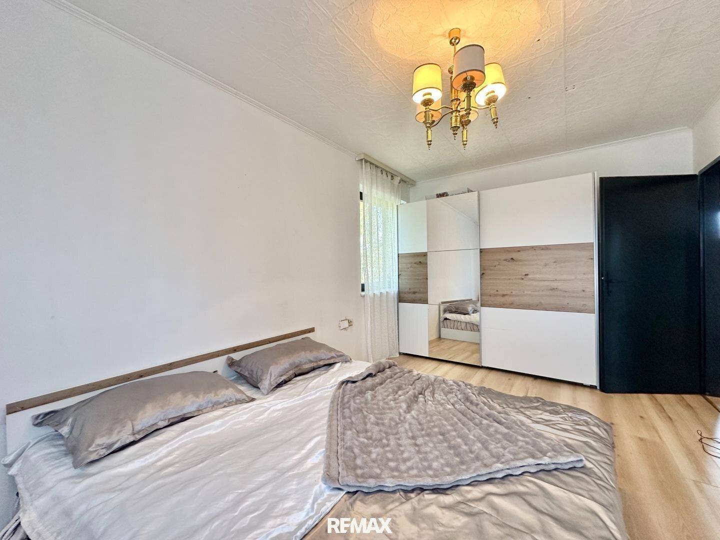 Schlafzimmer mit Doppelbett und einem großen Kleiderschrank mit Spiegeltüren.