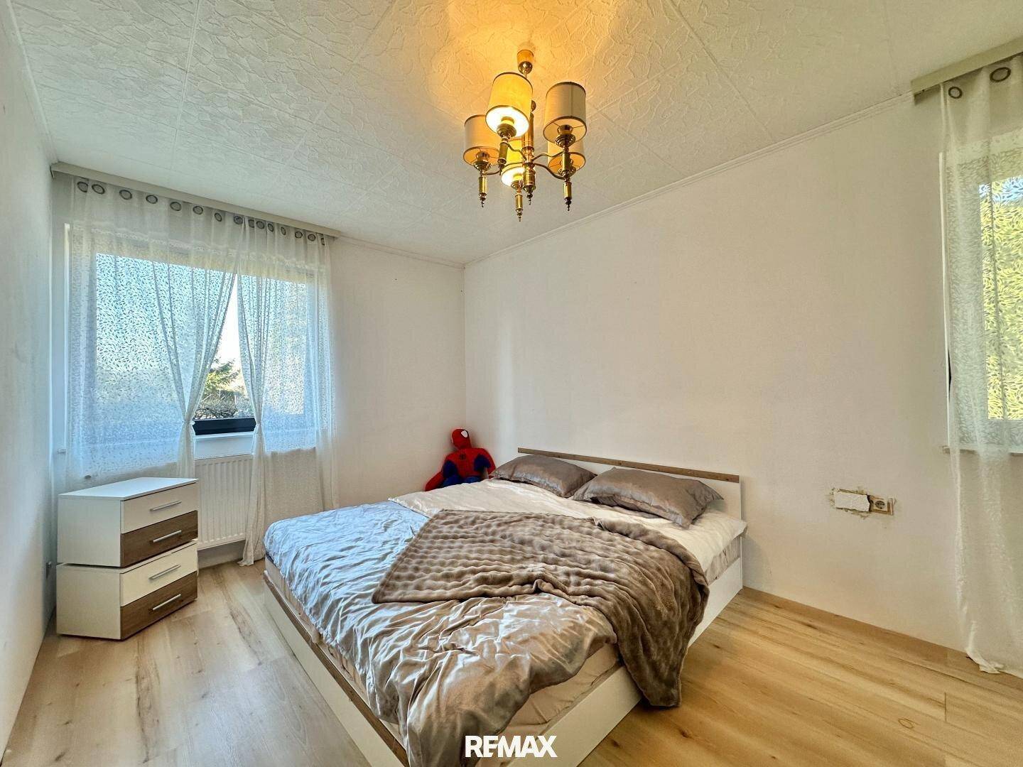 Schlafzimmer mit Doppelbett, Nachttischen und einem Fenster, das viel Licht hereinlässt.