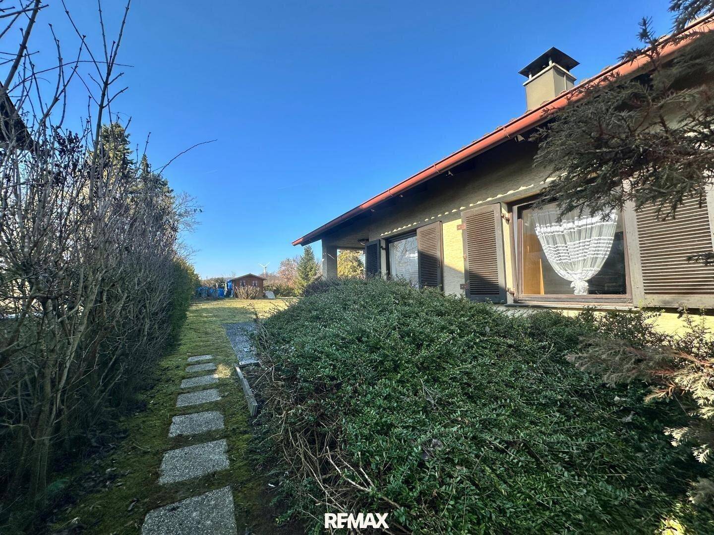 Seitlicher Blick auf das Haus mit einem Gartenweg und gepflegten Büschen.