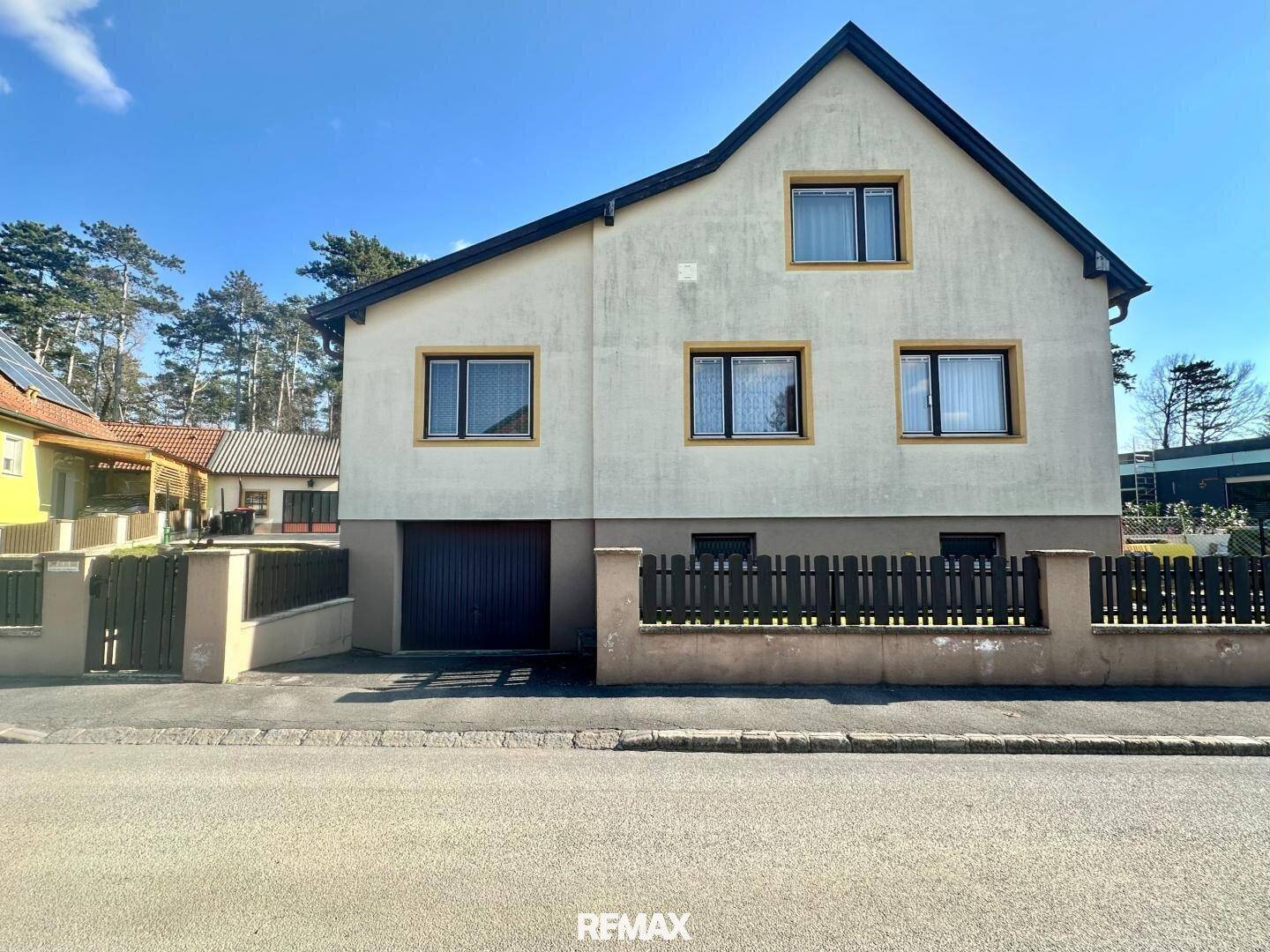 Vorderansicht des Hauses von der Straße aus mit Garage und mehreren Fenstern.