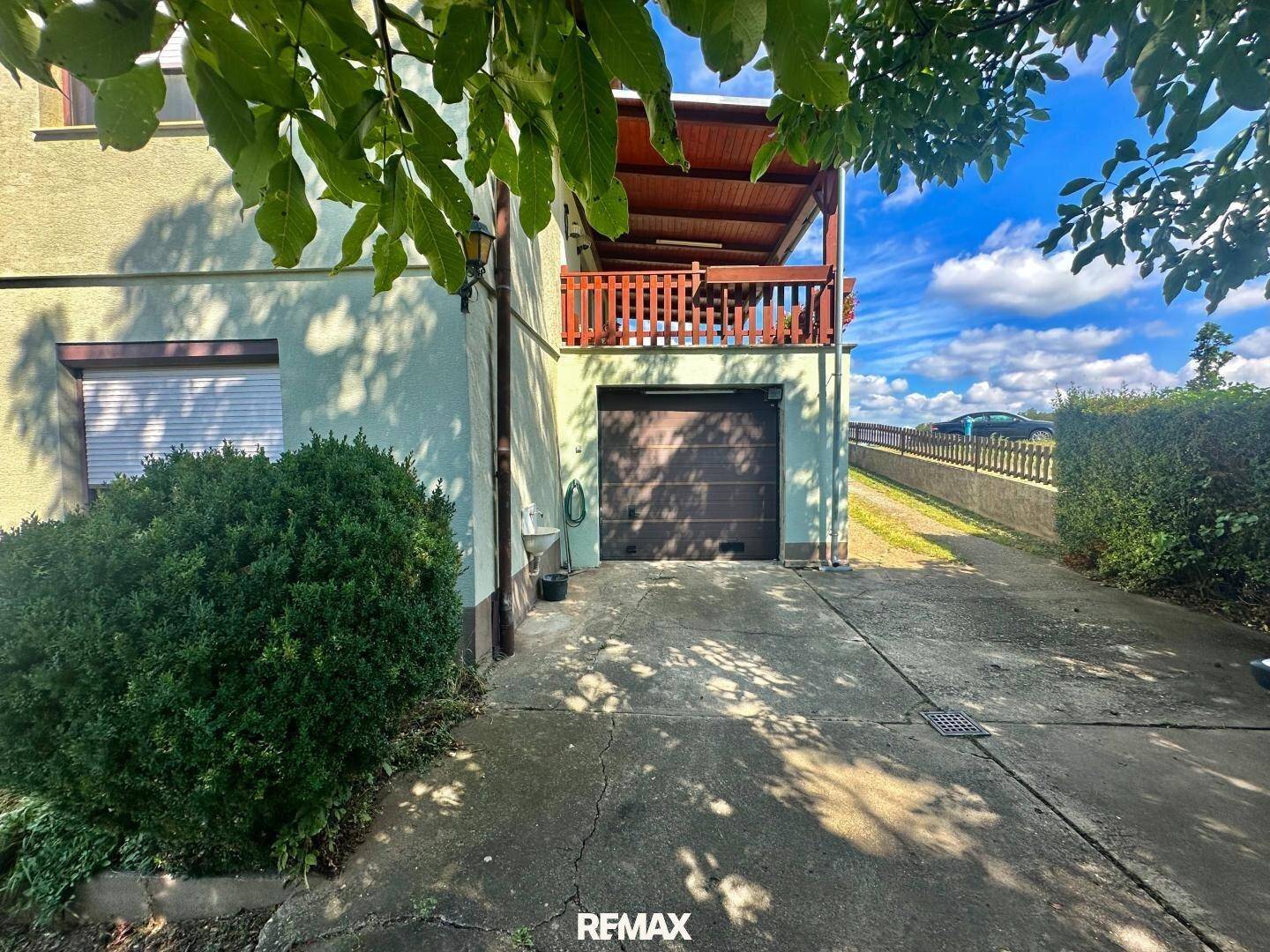Einfahrt zur Garage mit einem darüberliegenden Balkon und Holzgeländer.