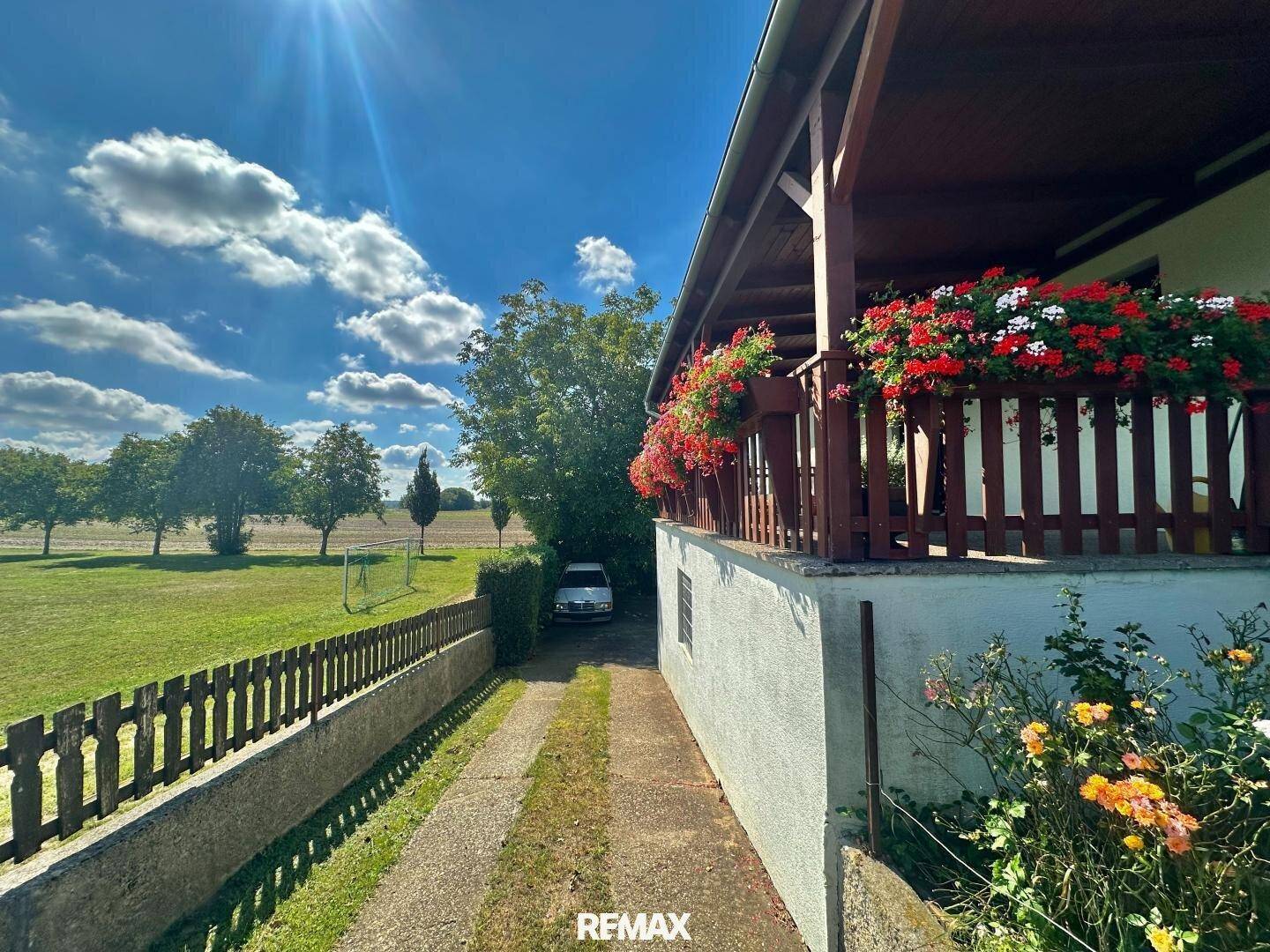 Seitenansicht des Hauses mit blumengeschmücktem Balkon und Blick auf die weite Landschaft.