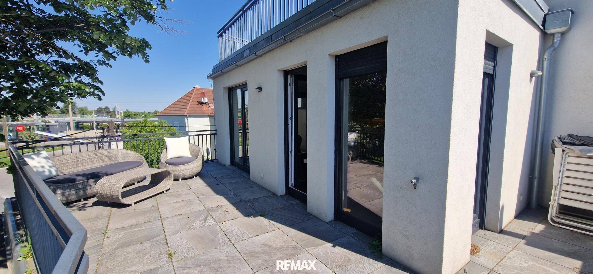 Große Sonnenterrasse mit Zugang zum Innenbereich und Blick ins Grüne.