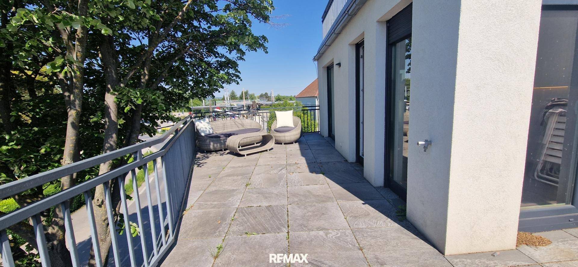 Geräumige Terrasse mit Steinplatten und Sitzgelegenheiten, umgeben von Bäumen.