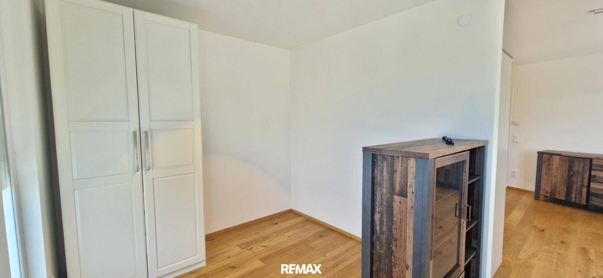 Helles Schlafzimmer mit Holzboden und weißem Kleiderschrank, bereit zur Einrichtung.