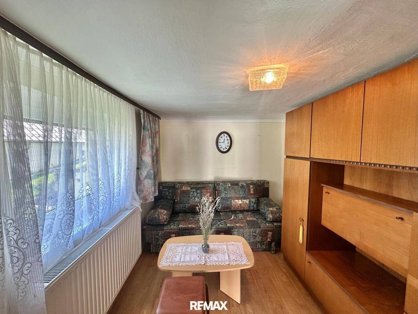 Kleiner Wohnraum mit Schlafsofa und praktischen Holzschränken, ideal als Gästezimmer nutzbar.