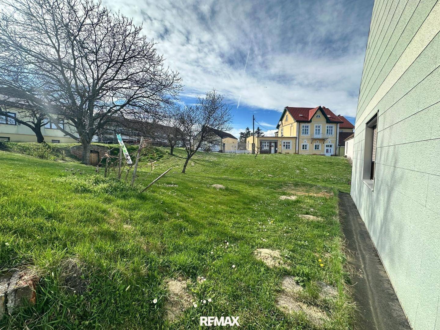 Weitläufiger Gartenbereich neben dem Haus mit Blick auf die umliegende Landschaft und weitere Gebäude.