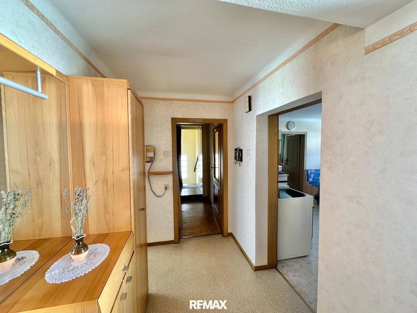 Geräumiger Flur mit Holzschrank und Blick in angrenzende Zimmer, typisch für ältere Gebäude.