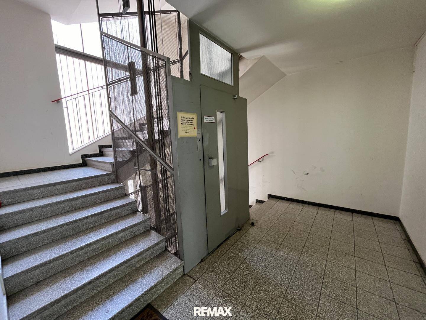 Treppenhaus mit Aufzug und Fliesenboden, bietet Zugang zu den oberen Etagen.