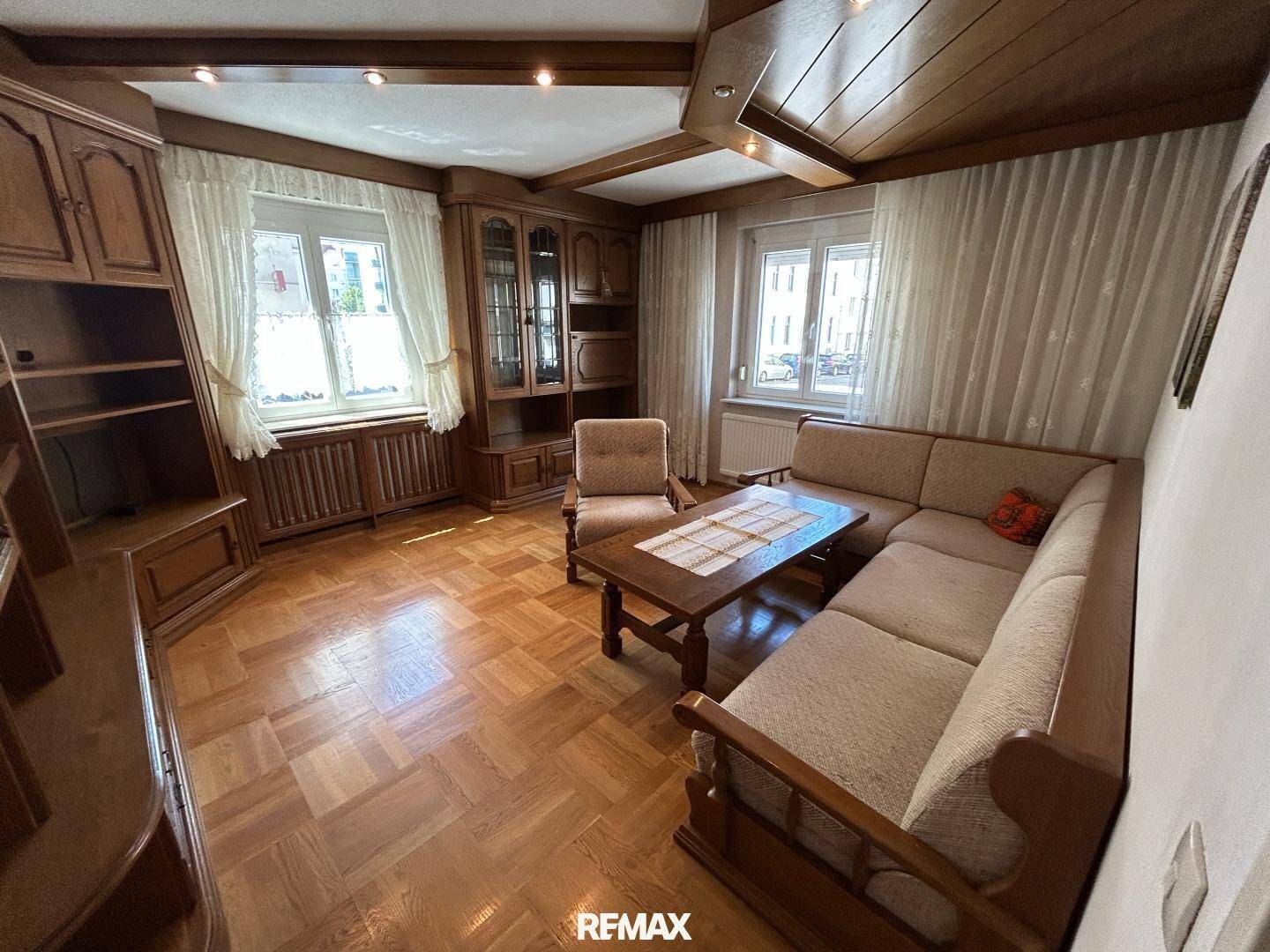 Gemütliches Wohnzimmer mit Holzparkett, Holzbalkendecke und traditionellen Holzmöbeln.