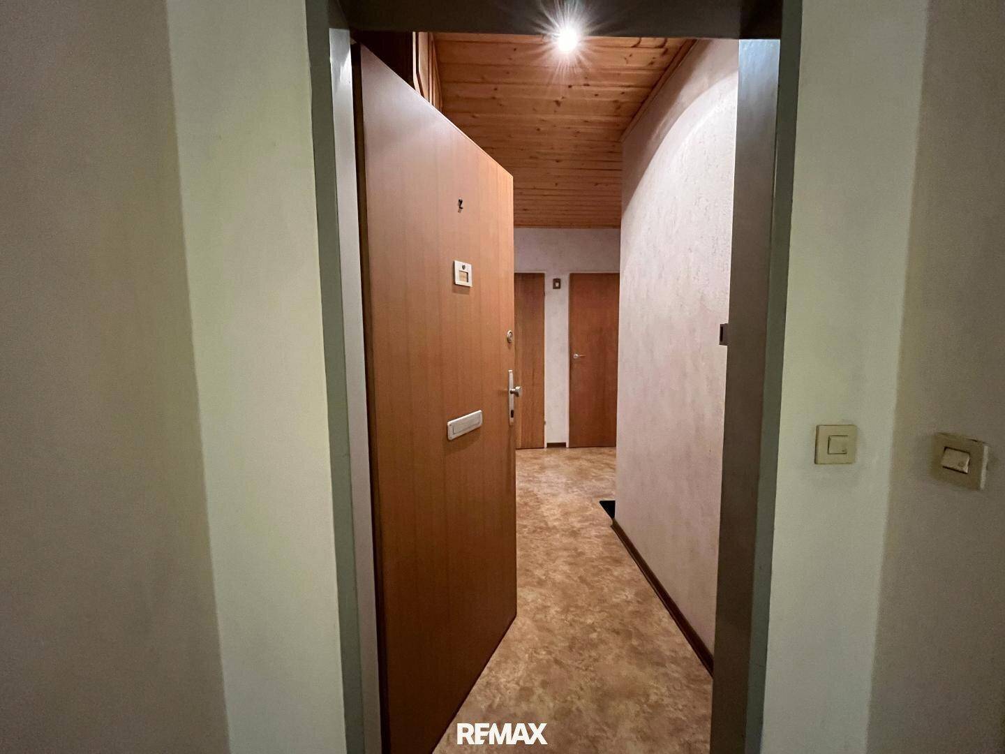 Eingangsbereich mit Holztür und Holzdecke, der zu den verschiedenen Räumen der Wohnung führt.