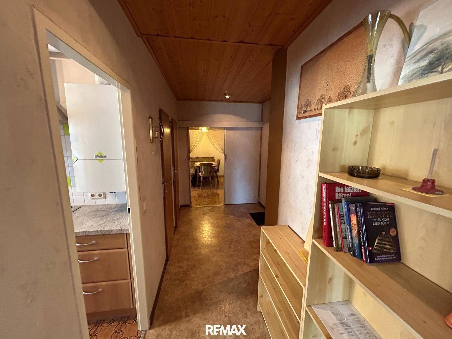 Geräumiger Flur mit Bücherregal und Blick in den Essbereich, mit Holzdecke.