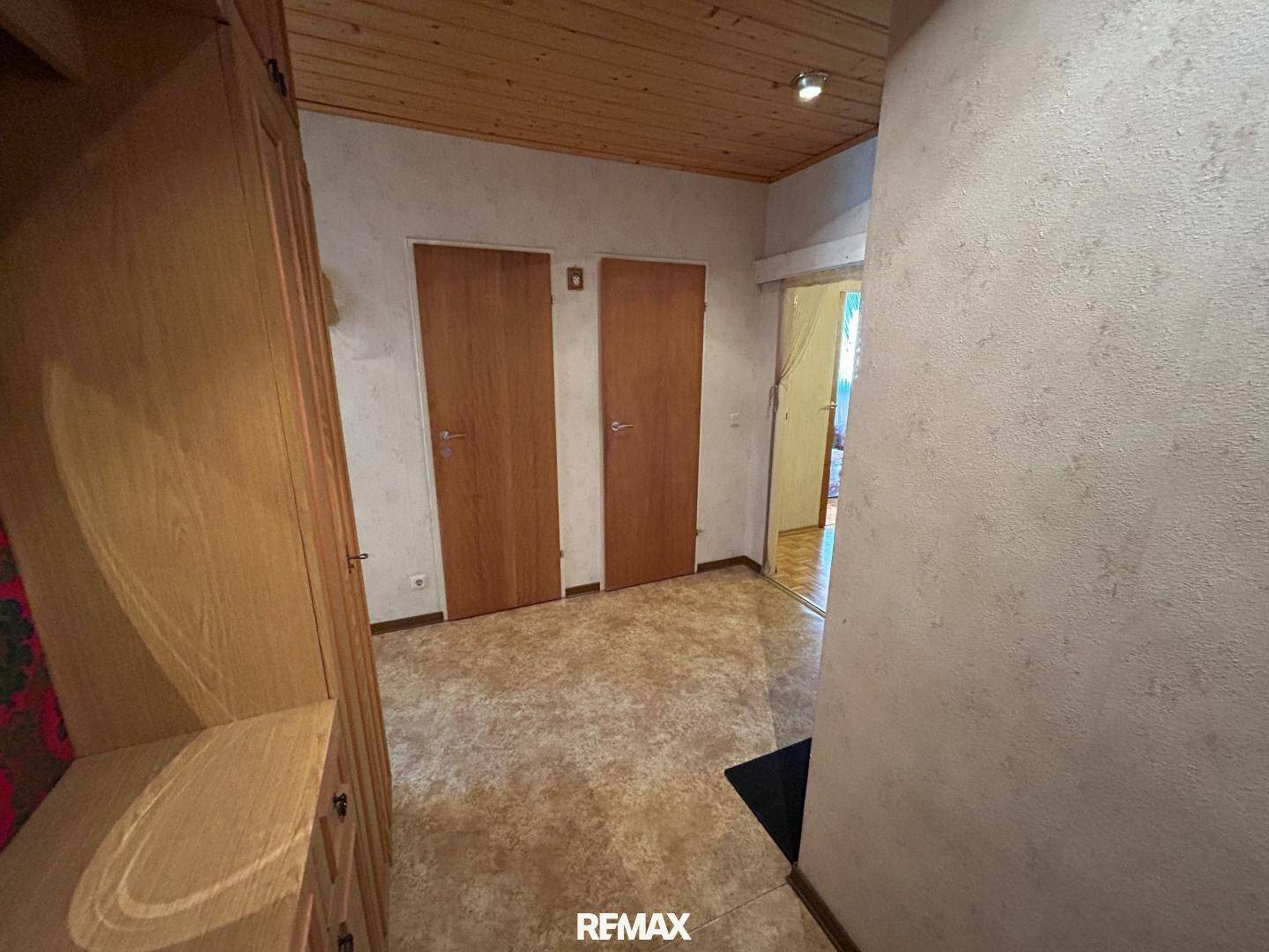 Heller Flur mit Holzdecke, Fliesenboden und praktischen Einbauschränken.