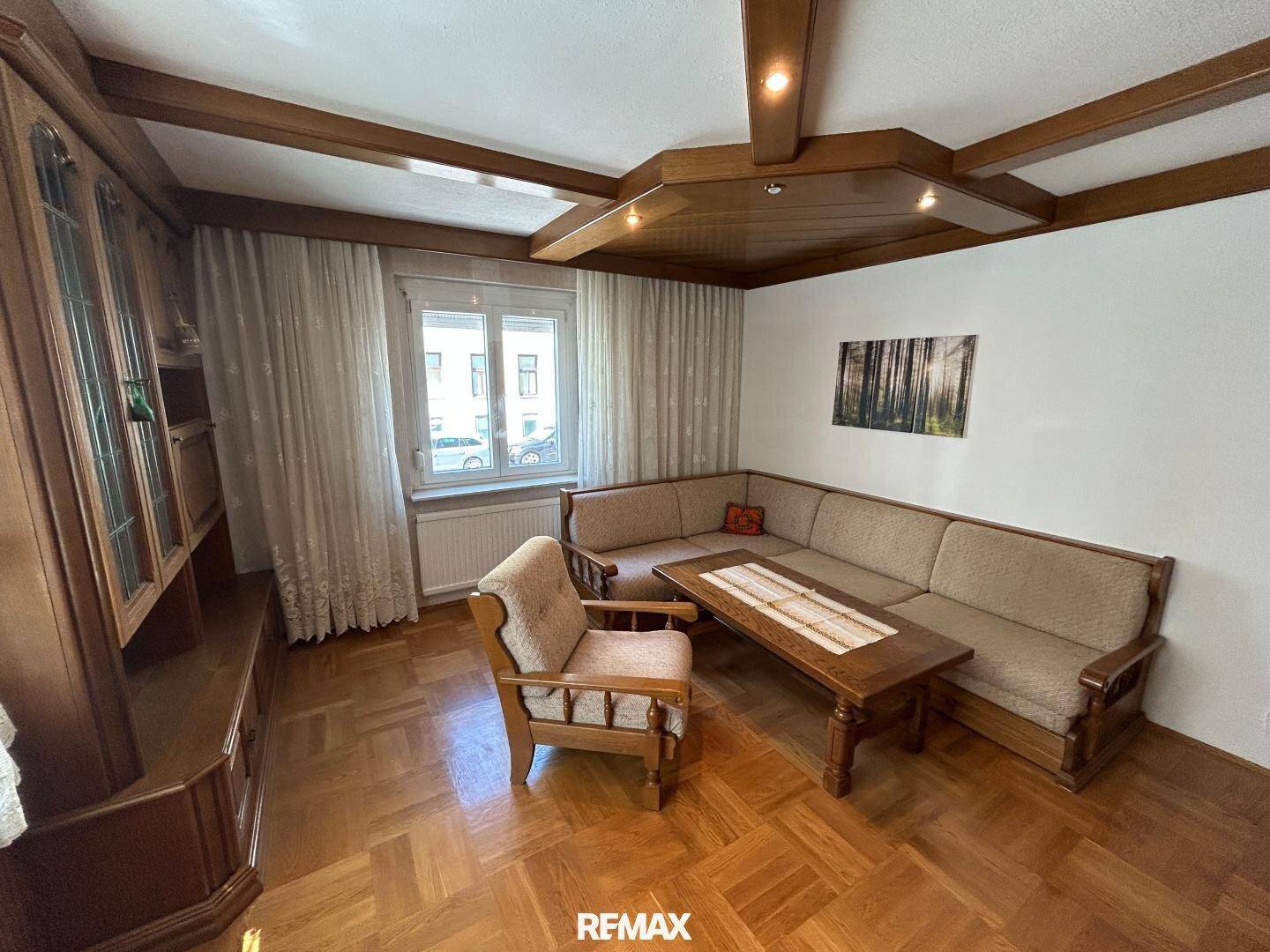 Helles Wohnzimmer mit klassischem Holzparkett und passenden Holzmöbeln, ideal zum Entspannen.