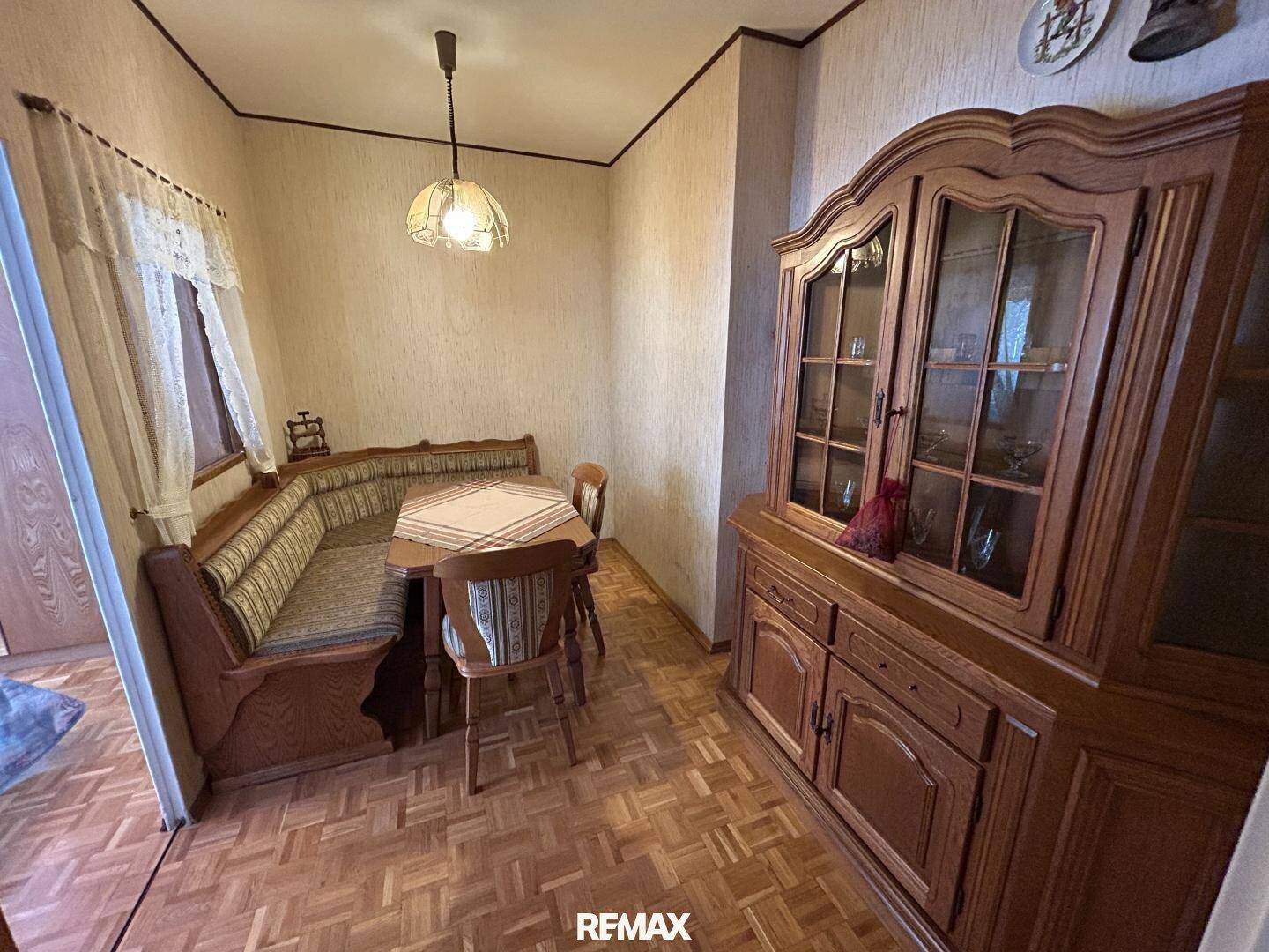 Essbereich mit traditioneller Eckbank, Holztisch und passendem Schrank, auf Parkettboden.