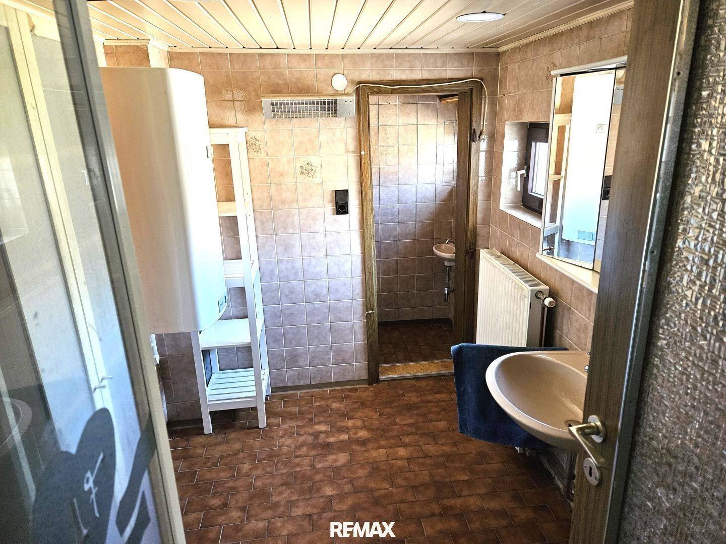 Badezimmer mit braunen Fliesen, Waschbecken und Spiegelschrank.