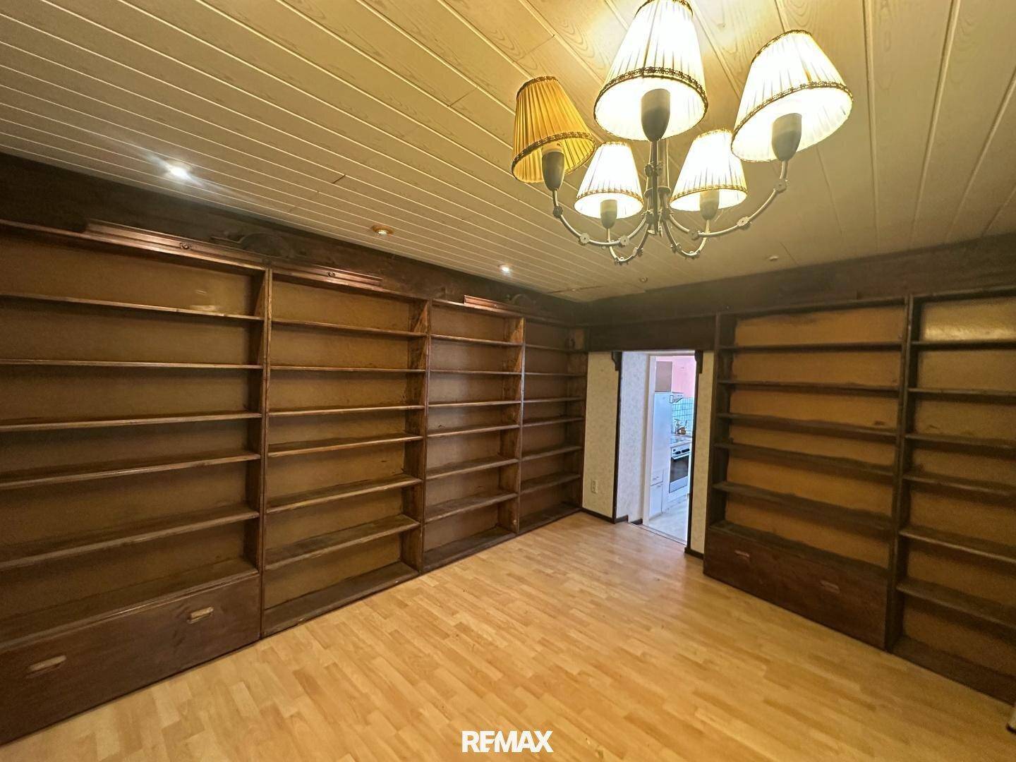 Geräumige Bibliothek mit raumhohen Holzregalen und Holzboden, ideal für Büchersammlungen.