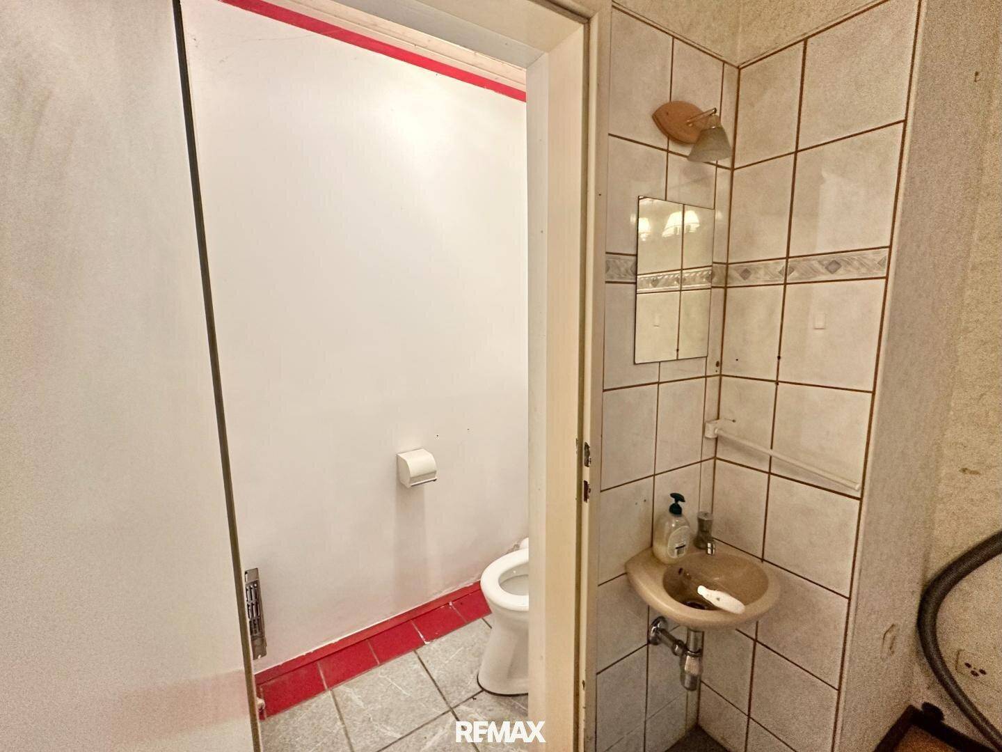 Kleines Gäste-WC mit Fliesenboden und einfacher Ausstattung, funktional und kompakt.