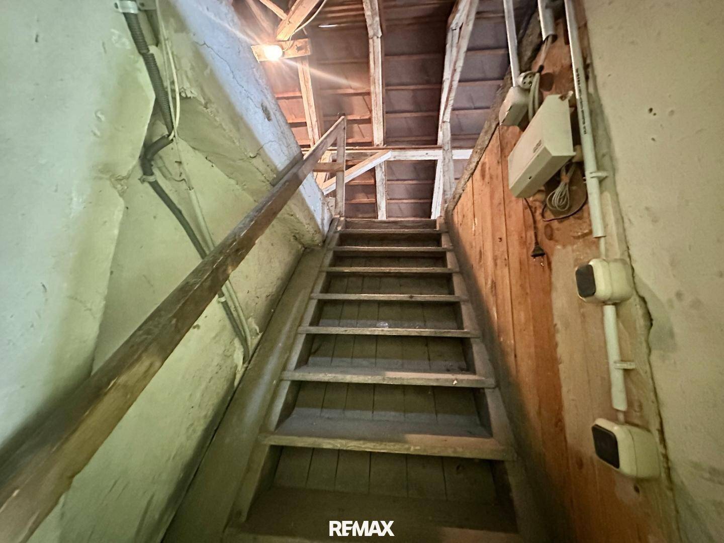 Rustikale Holztreppe in einem unfertigen Bereich mit sichtbaren Leitungen.