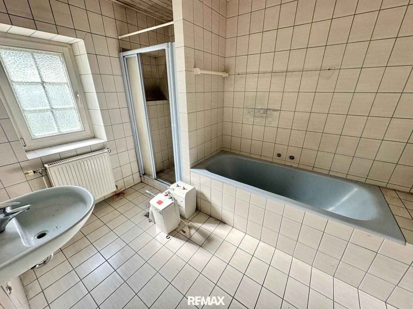 Badezimmer mit Badewanne, Duschkabine, Waschbecken und Fenster.
