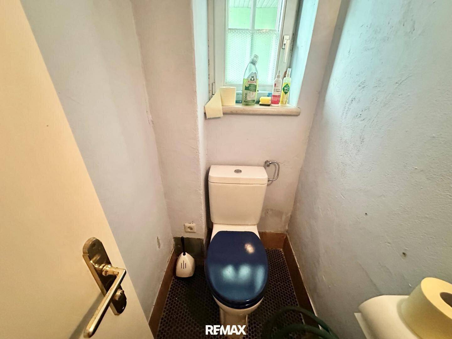 Kleines WC mit Fenster und einfacher Toilette, bietet natürliche Belüftung.