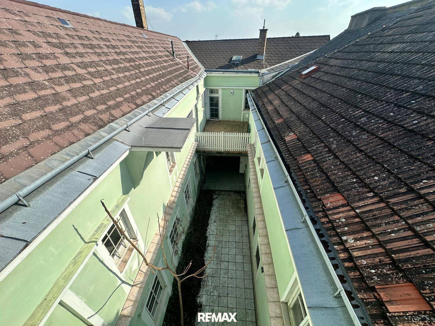 Vogelperspektive auf einen Innenhof mit hellgrünen Fassaden und roten Ziegeldächern.