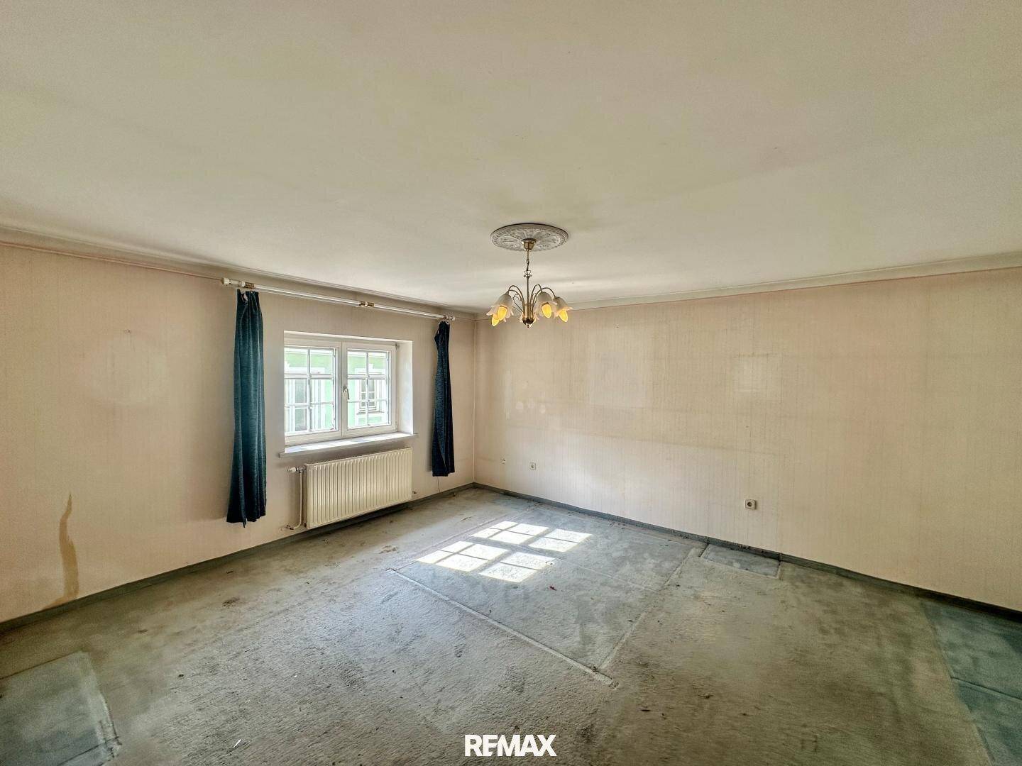 Geräumiges Zimmer mit Teppichboden, Fenster und Renovierungsbedarf.