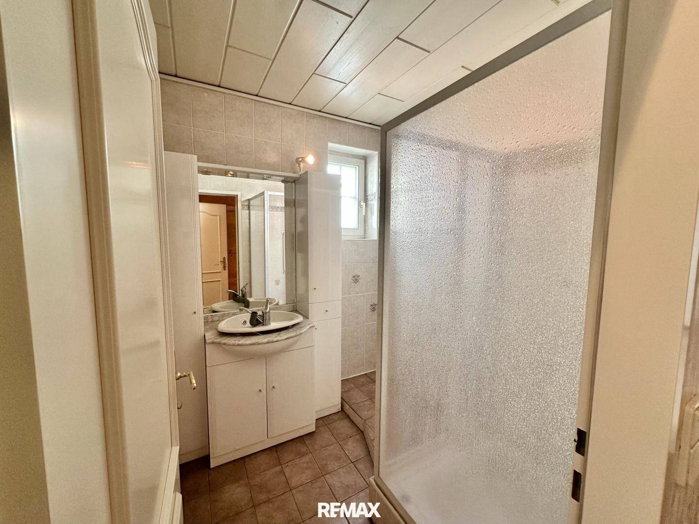 Badezimmer mit Waschbecken, Spiegelschrank und Duschkabine.