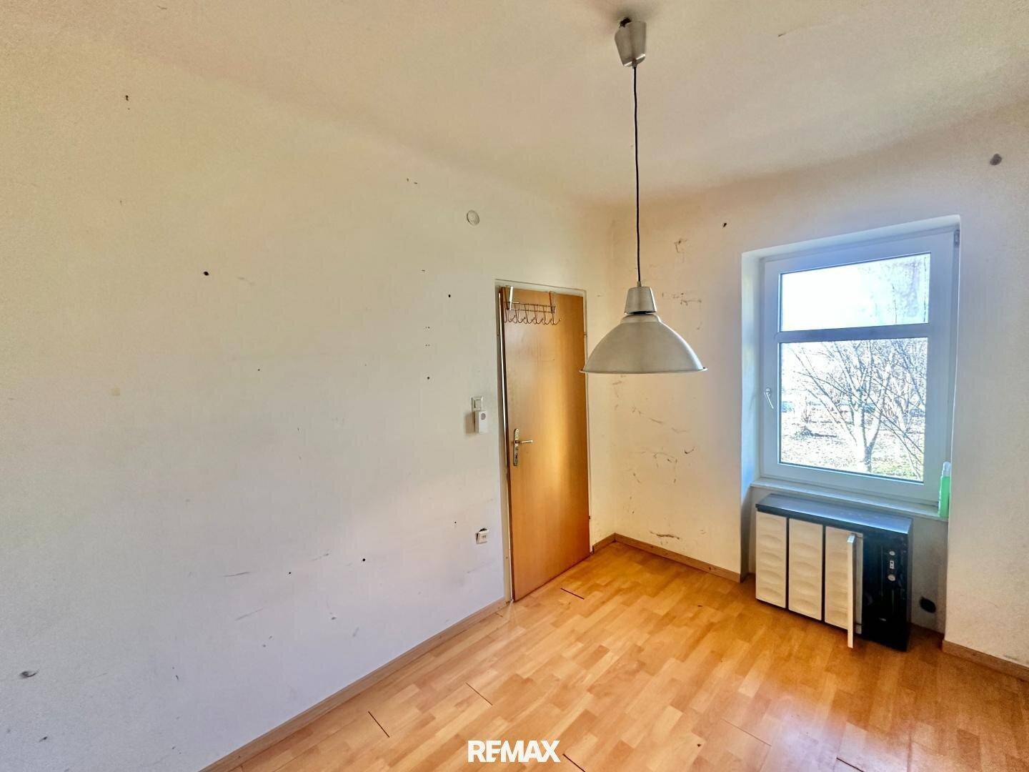 Einfaches Zimmer mit Parkettboden und einem Fenster, das für natürliche Belichtung sorgt.