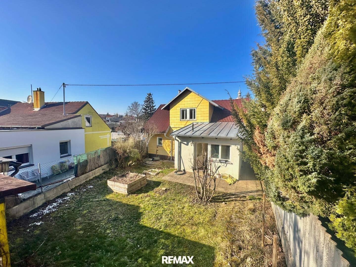 Blick von oben auf den Gartenbereich mit dem gelben Haus und einem kleinen Anbau.
