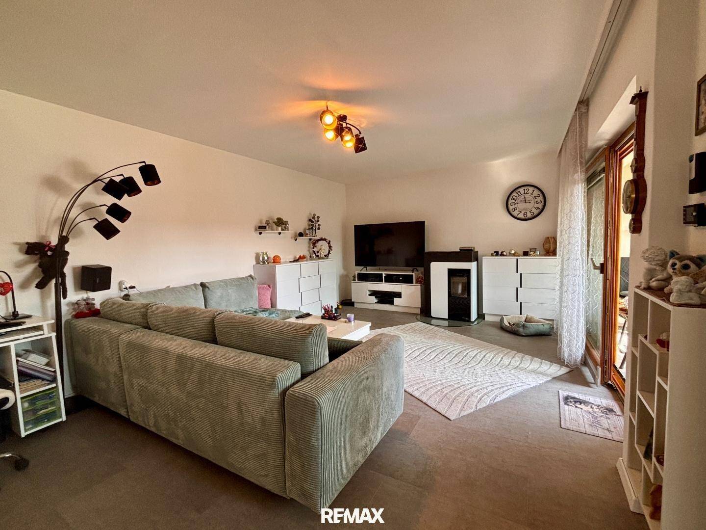 Geräumiges Wohnzimmer mit modernem Kaminofen, Sofa und Zugang zur Terrasse.